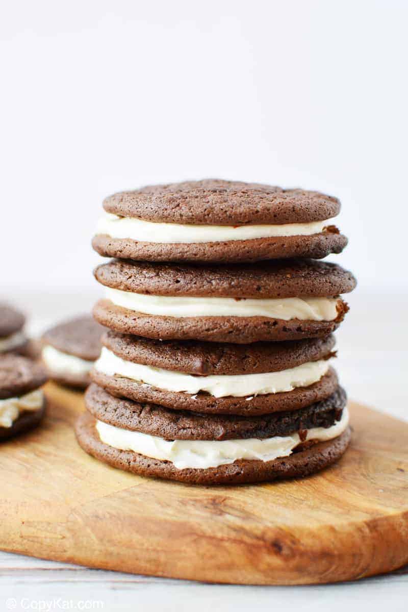 four chocolate sandwich cookies stacked on a wood board