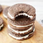 a stack of four chocolate sandwich cookies with a bite taken out of one