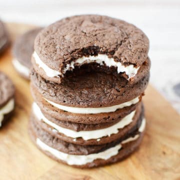 a stack of four chocolate sandwich cookies with a bite taken out of one