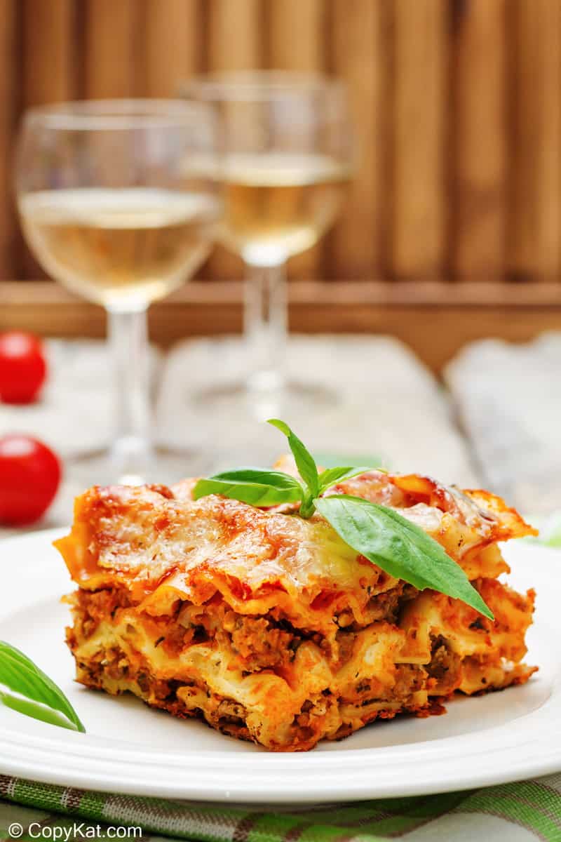homemade lasagna on a plate and two glasses of white wine