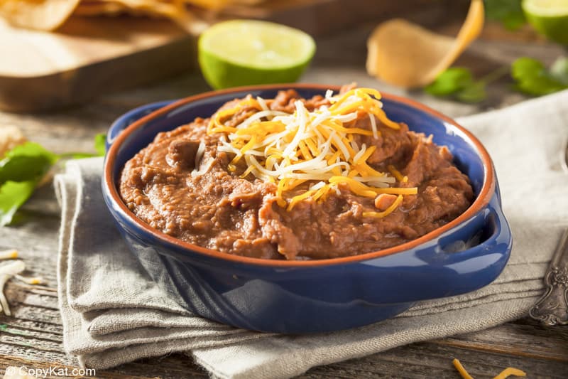 a bowl of homemade refried beans topped with shredded cheese in a bowl