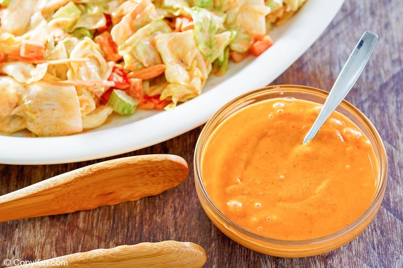 a bowl of homemade French salad dressing next to a salad