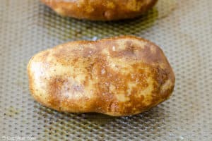 russet potato coated with oil and salt on a baking sheet