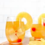 two glasses of pineapple white wine sangria on a cutting board