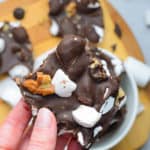 hand holding a piece of rocky road candy with walnuts