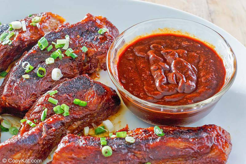 ribs and a bowl of homemade barbecue sauce on a plate