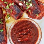 ribs and a bowl of homemade Sonny's BBQ sauce on a plate