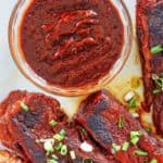 a bowl of homemade Sonny's BBQ sauce and ribs on a plate