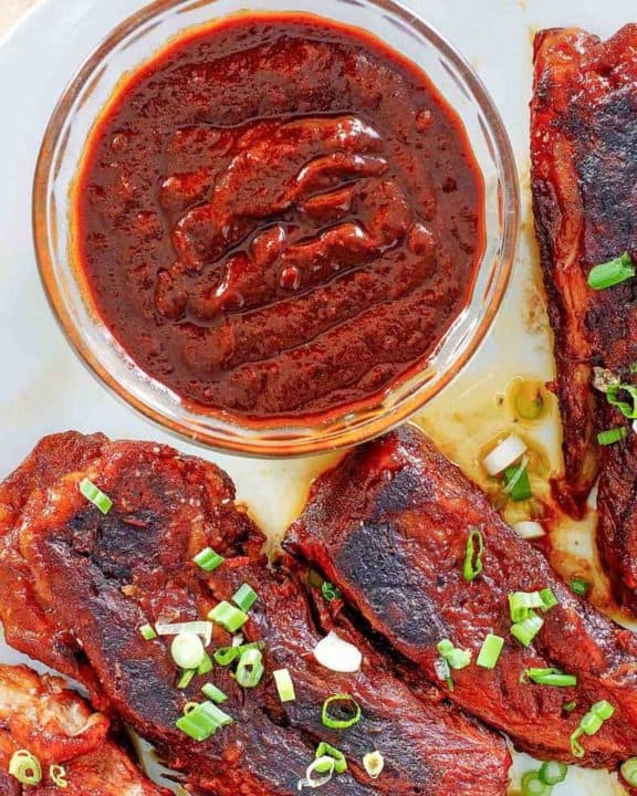 a bowl of homemade Sonny's BBQ sauce and ribs on a plate