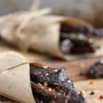 homemade spicy beef jerky wrapped in parchment paper and peppercorns