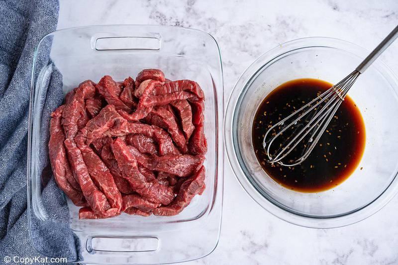 beef strips in a dish and teriyaki marinade in a bowl