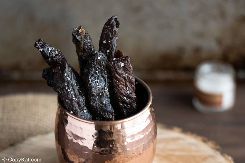 strips of homemade teriyaki beef jerky in a cup