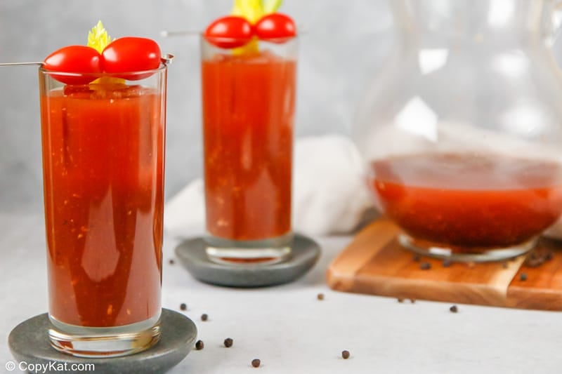 two bloody mary cocktails and bloody mary mix in a pitcher