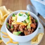 homemade chili with beans topped with cheese, sour cream, and avocado