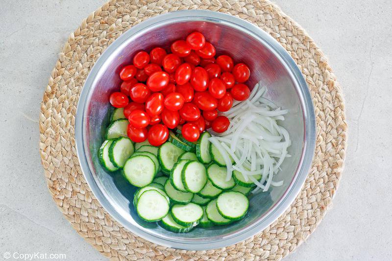 grape tomatoes, sliced cucumber, and sliced onion in a bowl
