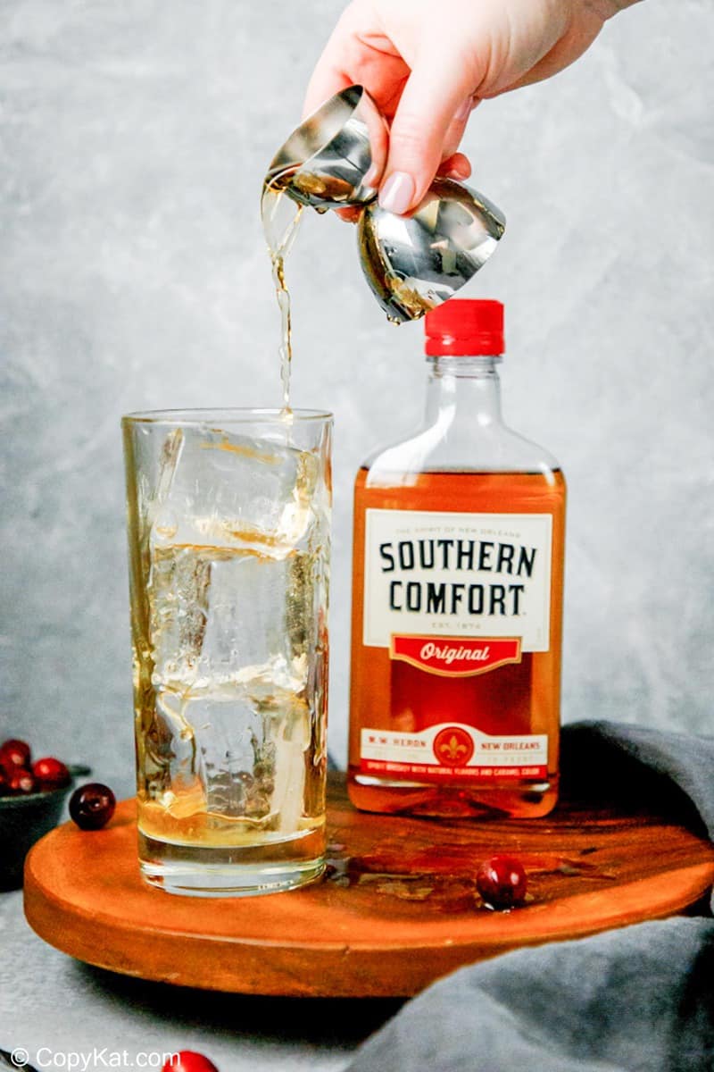 pouring southern comfort over ice in a glass