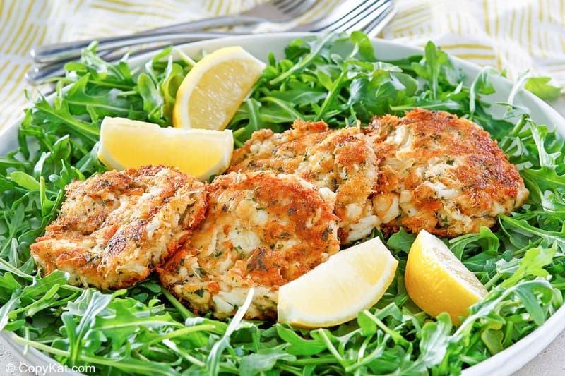 Maryland crab cakes and lemon wedges on top of arugula