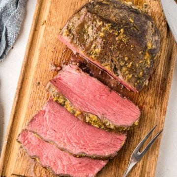 overhead view of cooked and sliced NY strip roast on a cutting board