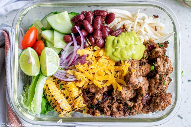 taco bowl with ground beef, cheese, guacamole, beans, and vegetables