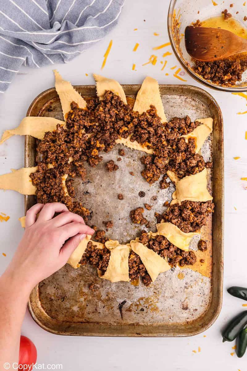 folding crescent roll triangles over ground beef