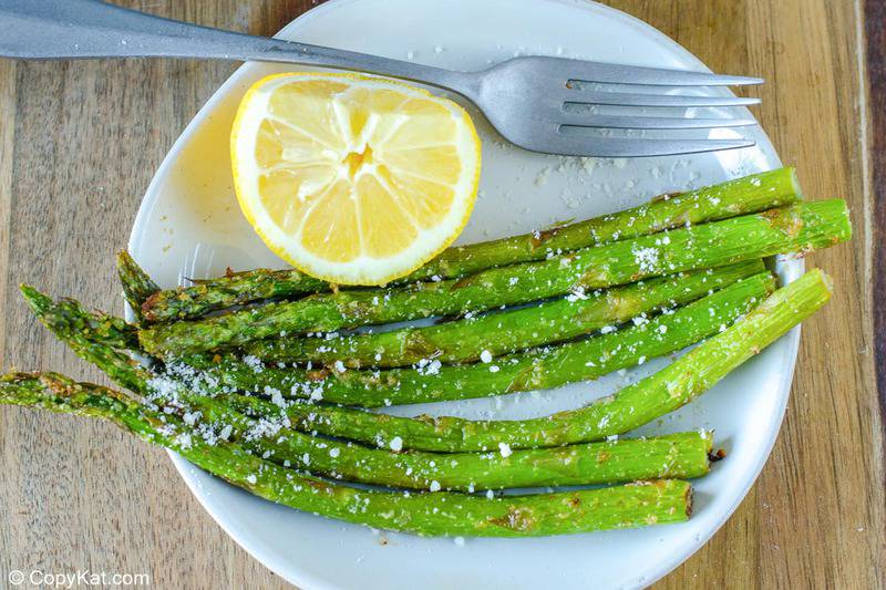 air fryer asparagus, lemon, and a fork on a plate