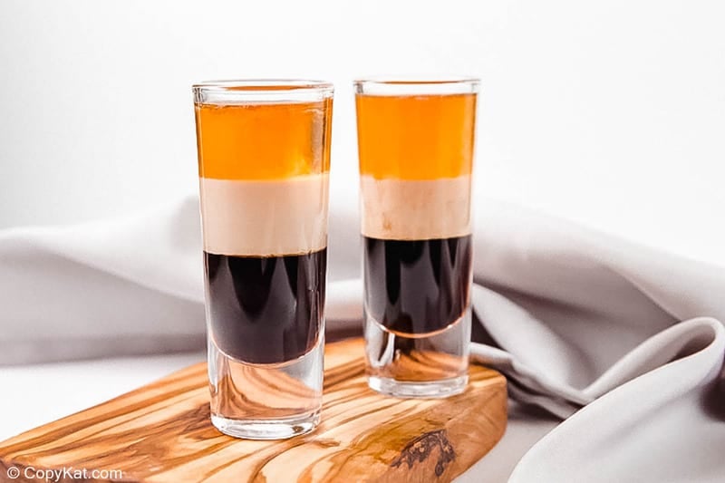 two B52 shot drinks on a wood board in front of a cloth napkin