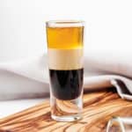 homemade TGI Friday's B52 shot on a wood board in front of a cloth napkin