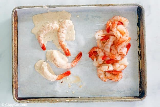 raw shrimp and shrimp coated in beer batter on a baking sheet