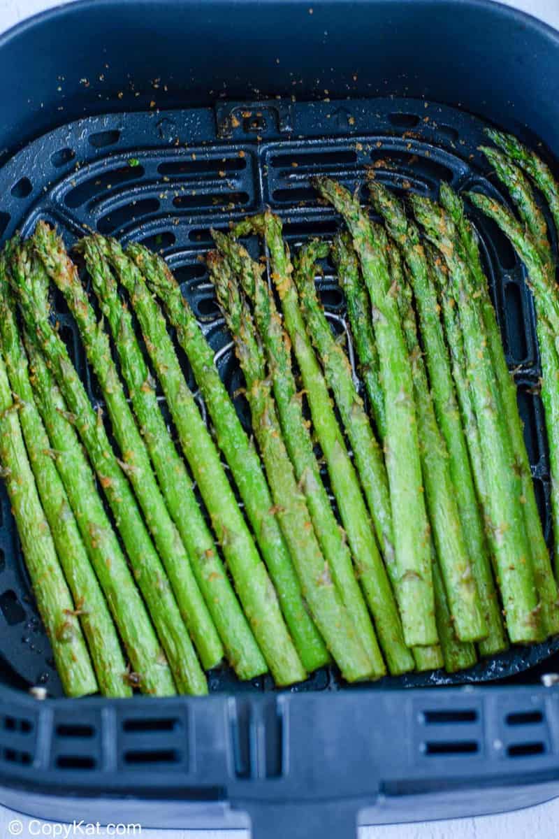 cooked asparagus in an air fryer basket