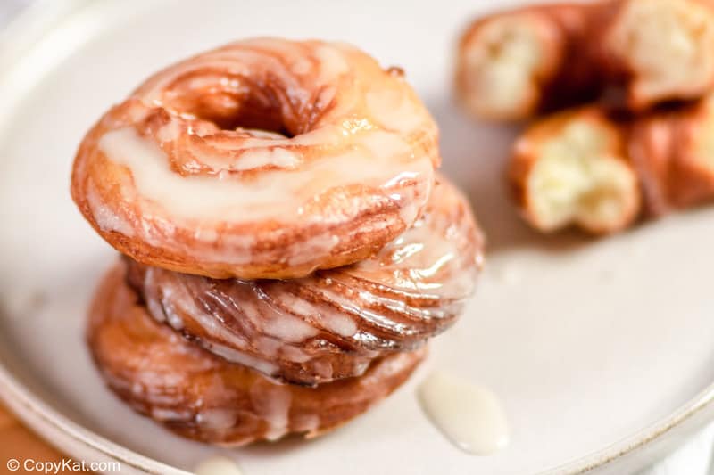 four homemade Dunkin Donuts French Cruller donuts with glaze on a plate