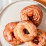four glazed French cruller donuts on a plate