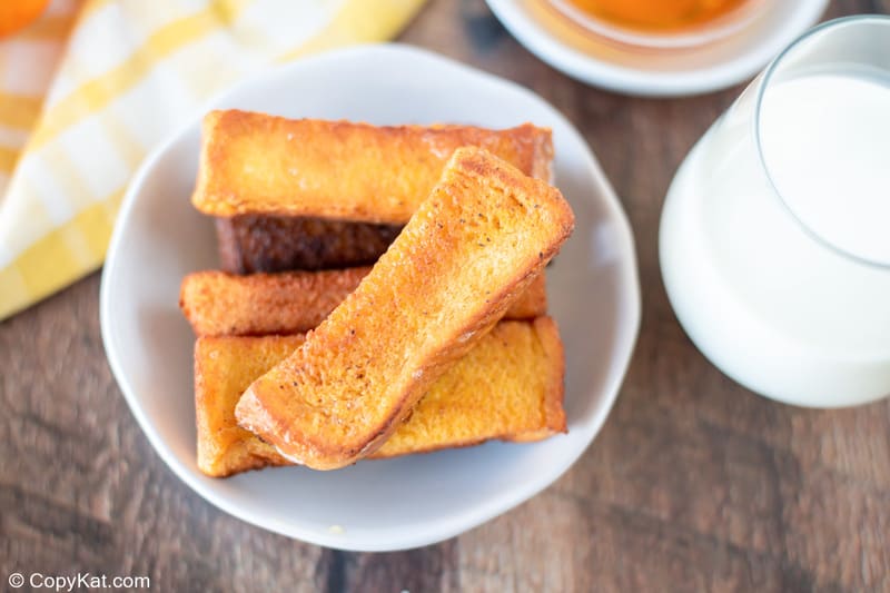 homemade Burger King French Toast Sticks in a bowl and a glass of milk