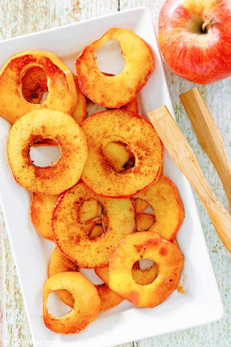 overhead view of fried apples, an apple, and wood tongs