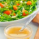 homemade Italian dressing in a small bowl next to a salad