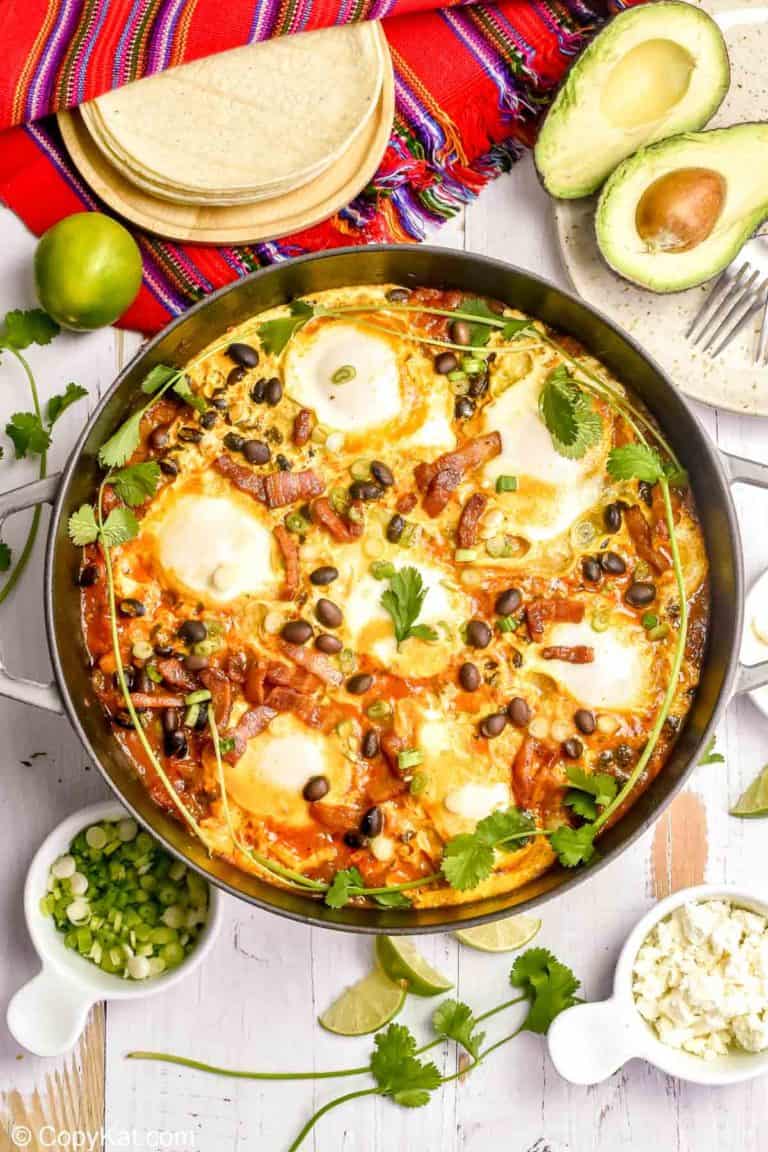huevos rancheros in a pan, corn tortillas, avocado, and cojita cheese