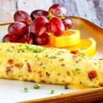 bacon and cheese omelette and fruit on a plate