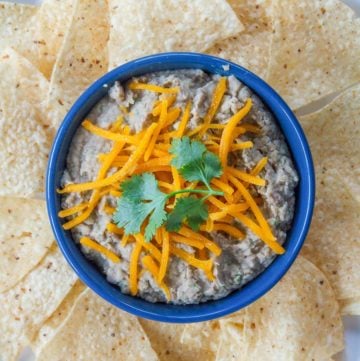 a bowl of refried beans and tortilla chips on a platter