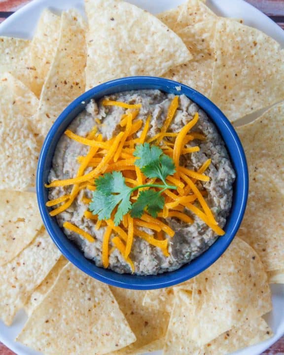 a bowl of refried beans and tortilla chips on a platter