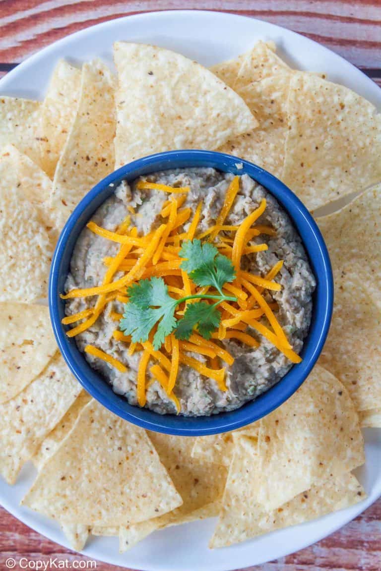 a bowl of refried beans and tortilla chips on a platter