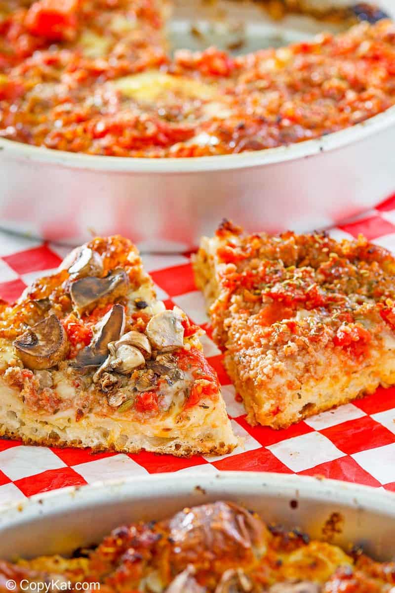 homemade deep dish pizza in pans and slices on parchment paper
