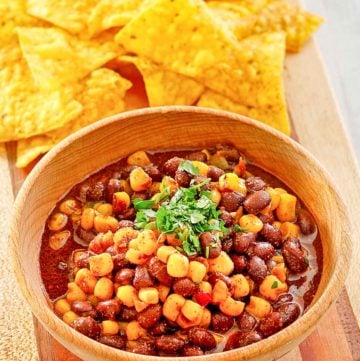 a bowl of black bean and corn salad next to tortilla chips