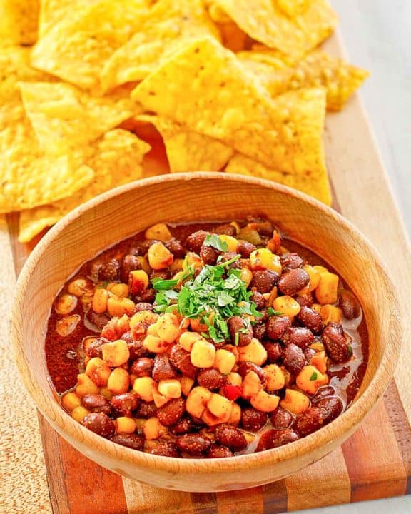 a bowl of black bean and corn salad next to tortilla chips