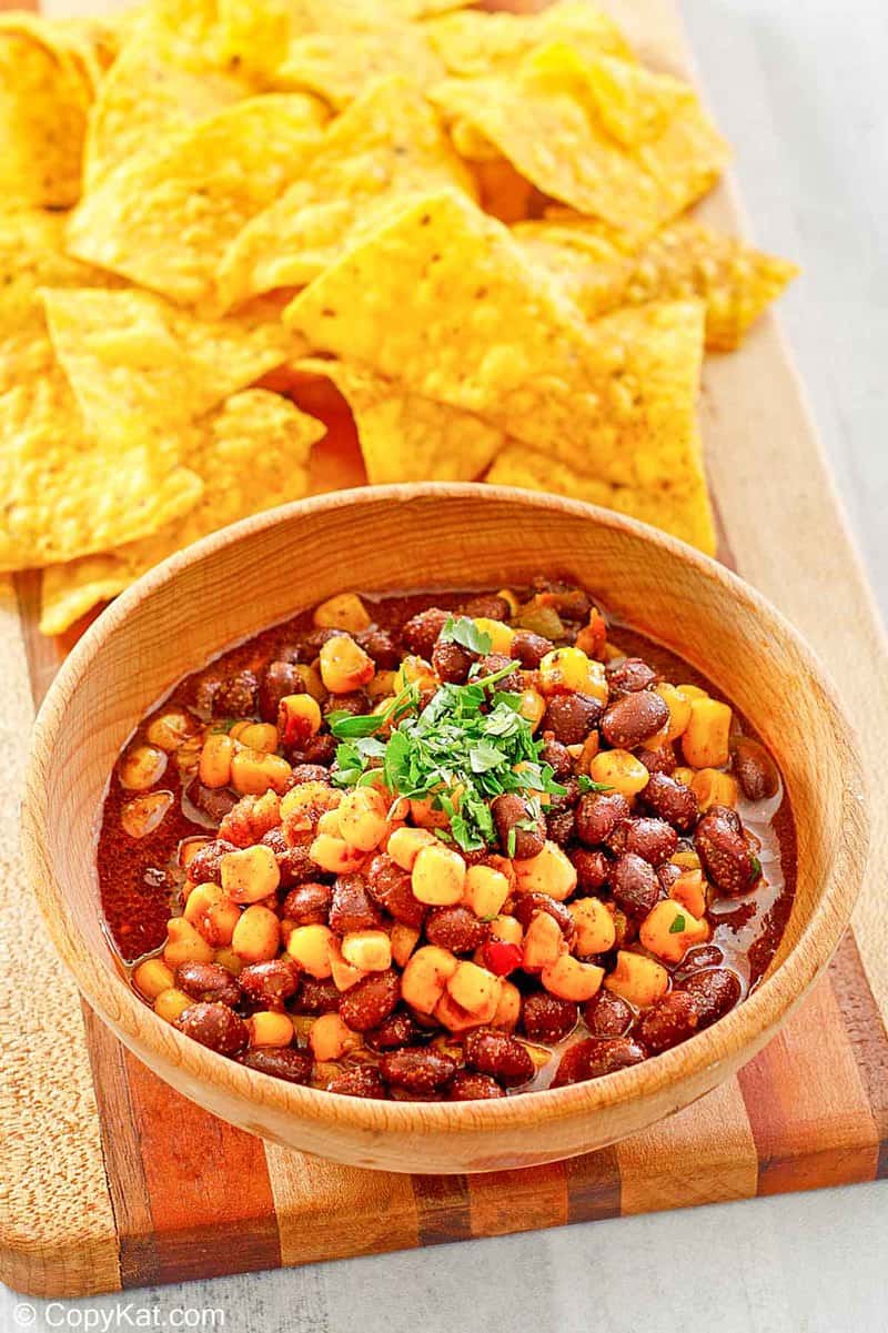 a bowl of black bean and corn salad next to tortilla chips