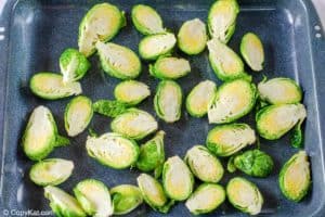 olive oil coated brussel sprout halves on a baking sheet