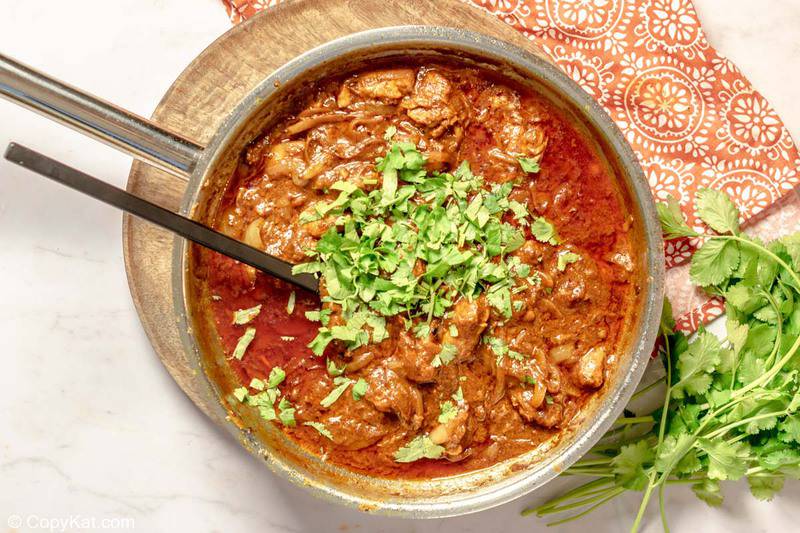 butter chicken topped with chopped fresh cilantro in a pan