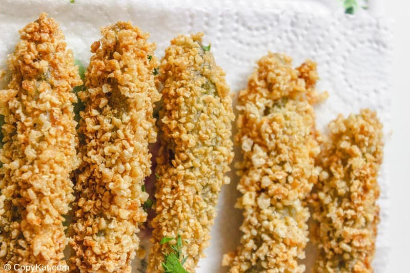 deep fried pickle spears draining on paper towels