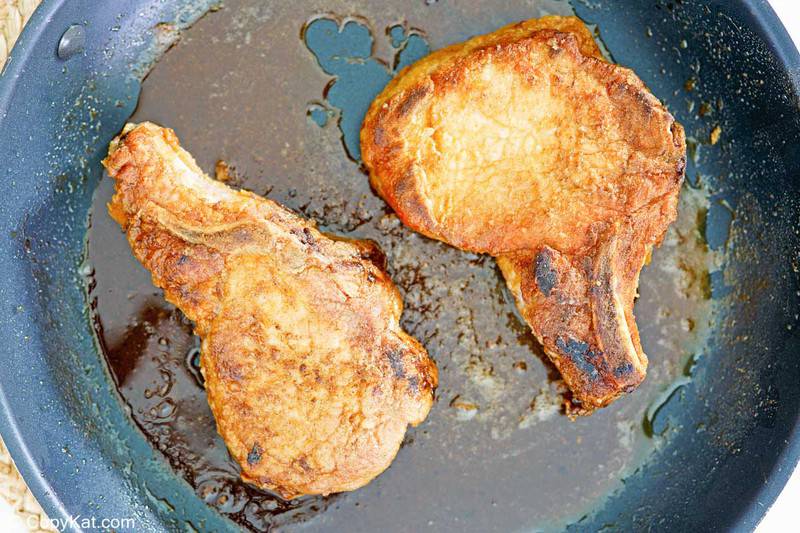 two fried breaded pork chops in a skillet