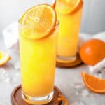 two fuzzy navel cocktail drinks garnished with orange slices