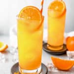 two fuzzy navel cocktail drinks and orange wedges