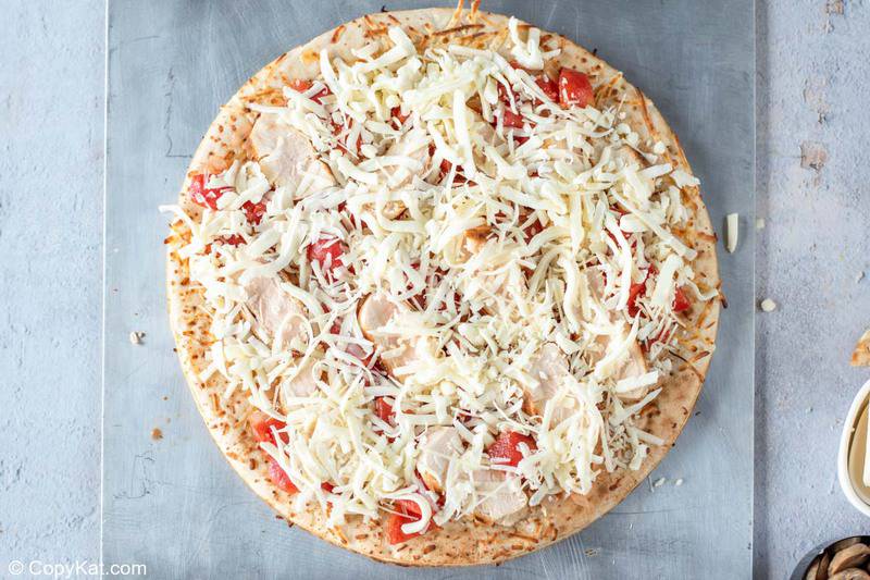 pizza crust topped with tomatoes, chicken, and cheese